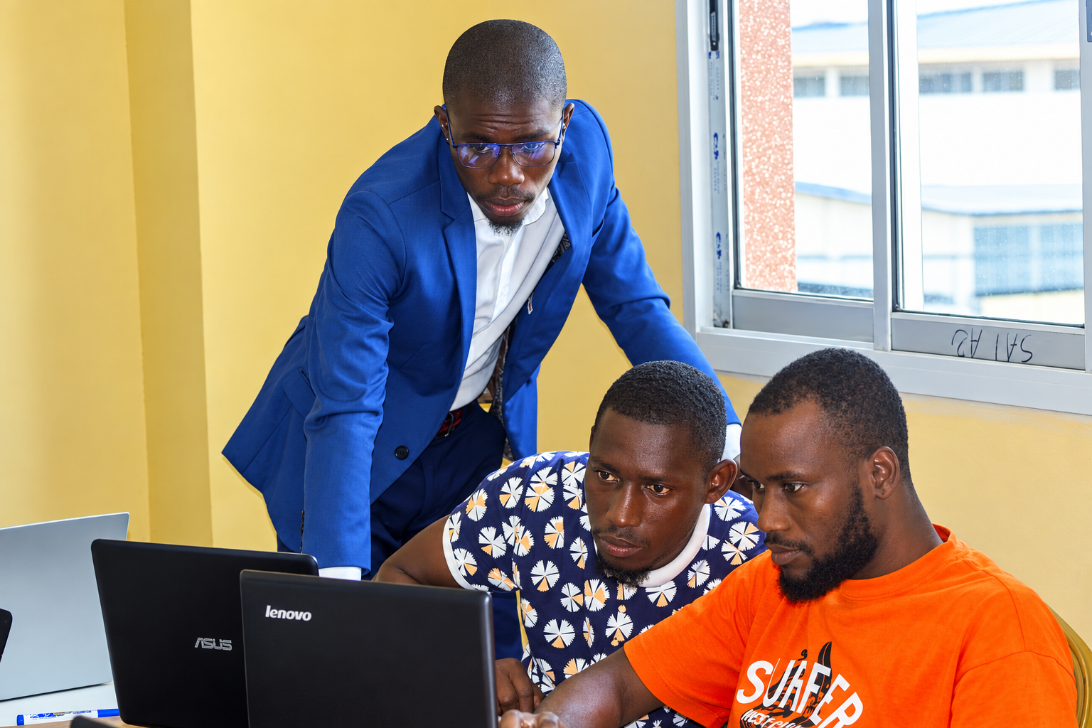 Formateur accompagnant deux apprenants en session chez CodeCodeur